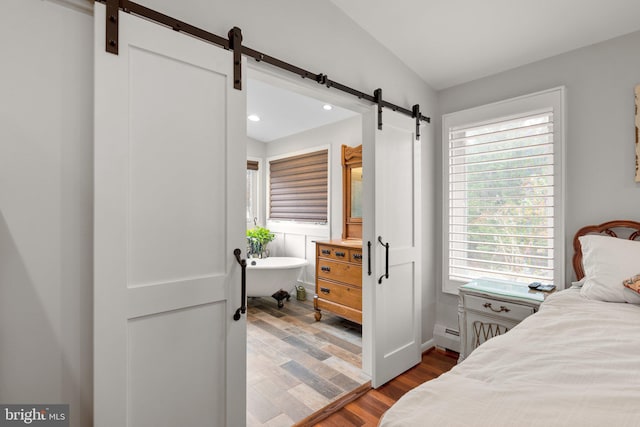 bedroom featuring baseboard heating, recessed lighting, a barn door, and wood finished floors