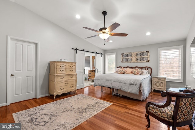 bedroom featuring ceiling fan, a barn door, vaulted ceiling, recessed lighting, and wood finished floors