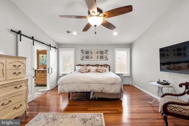 bedroom featuring a barn door, wood-type flooring, lofted ceiling, and visible vents