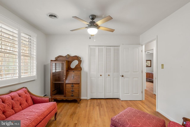 sitting room featuring baseboards, light wood-style floors, visible vents, and ceiling fan