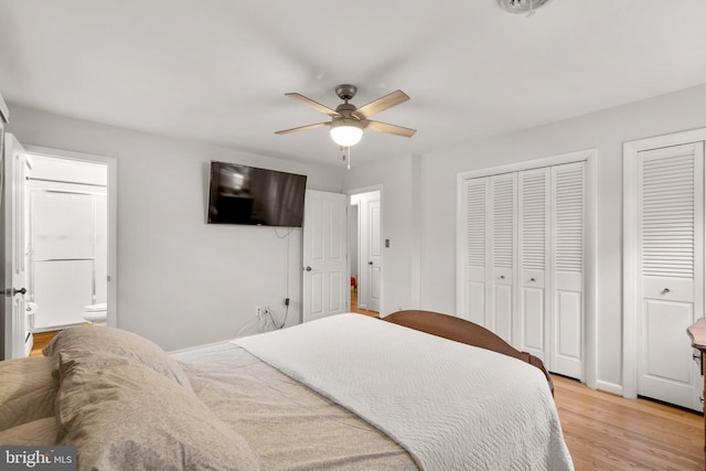 bedroom featuring multiple closets, connected bathroom, light wood-style floors, baseboards, and ceiling fan