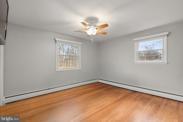 spare room featuring a baseboard heating unit, a ceiling fan, and wood finished floors