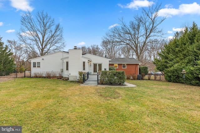 back of property featuring a lawn, a chimney, and fence