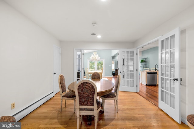 dining room featuring an inviting chandelier, light wood finished floors, french doors, and baseboard heating