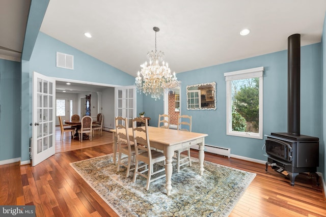 dining room with vaulted ceiling, visible vents, french doors, and hardwood / wood-style flooring