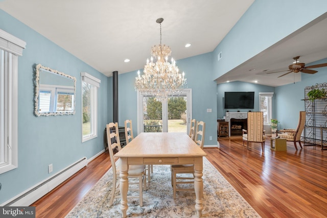 dining area featuring vaulted ceiling, wood finished floors, a healthy amount of sunlight, and baseboard heating