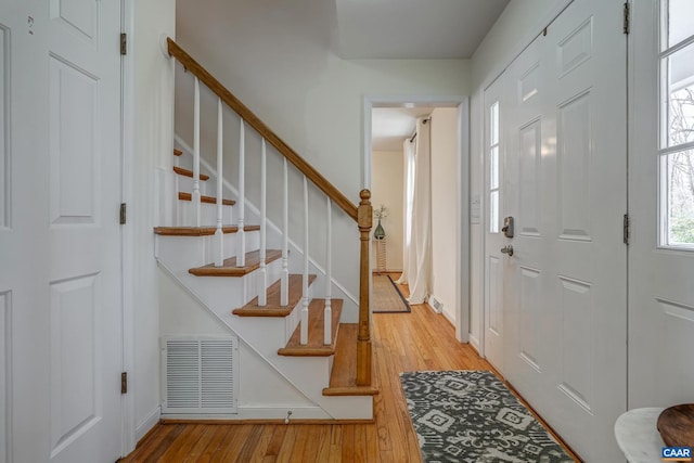 foyer with hardwood / wood-style floors, stairs, and visible vents