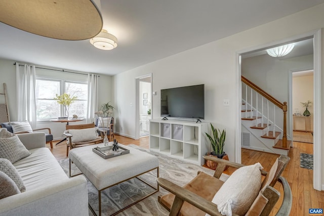 living area featuring visible vents, baseboards, stairs, and light wood-style floors