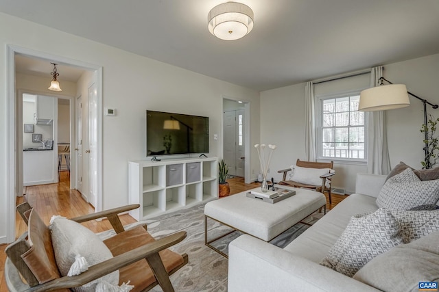 living area with visible vents, light wood-type flooring, and baseboards