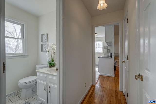 hall featuring a sink, visible vents, and light wood-style floors