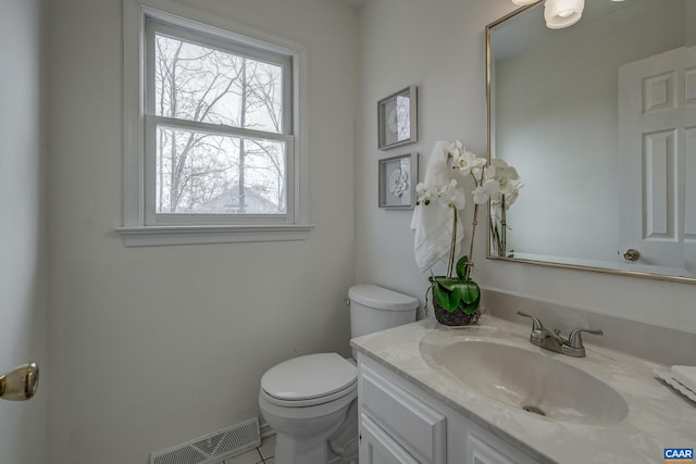 bathroom featuring vanity, toilet, and visible vents