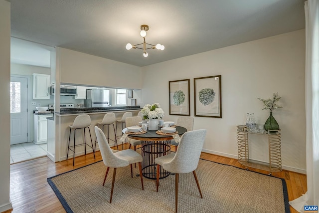 dining room with baseboards, an inviting chandelier, and light wood finished floors