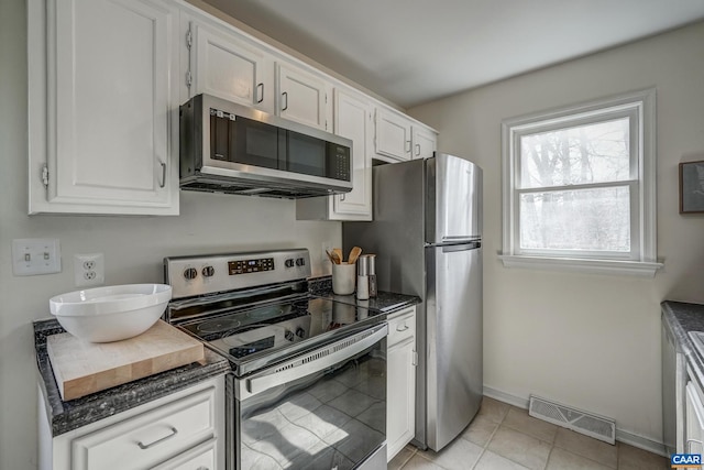 kitchen with visible vents, appliances with stainless steel finishes, white cabinets, light tile patterned floors, and baseboards