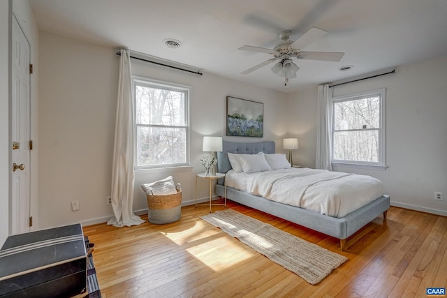 bedroom featuring visible vents, baseboards, a ceiling fan, and hardwood / wood-style flooring