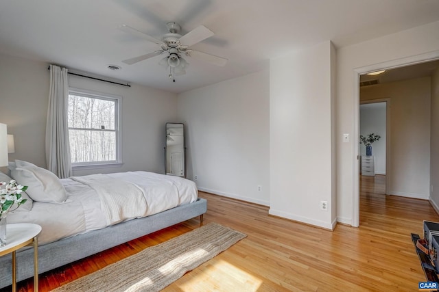 bedroom featuring light wood finished floors, visible vents, a ceiling fan, and baseboards