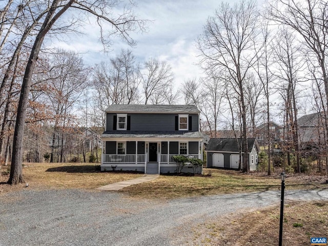 view of front of property featuring covered porch, driveway, a shingled roof, and an outdoor structure