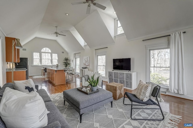 living area featuring high vaulted ceiling, light wood-style floors, and a ceiling fan