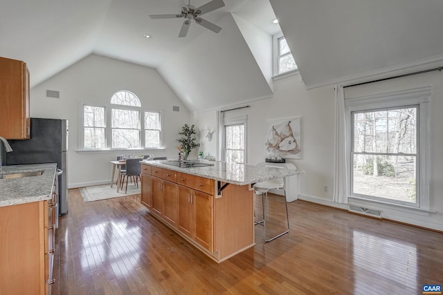 kitchen with a wealth of natural light, visible vents, a kitchen island, and brown cabinetry