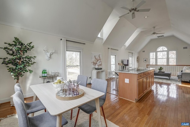 dining room featuring visible vents, plenty of natural light, lofted ceiling, and light wood finished floors