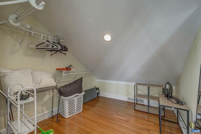 interior space with baseboards, lofted ceiling, and wood finished floors