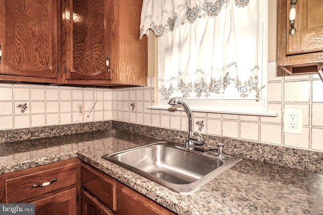 kitchen featuring a sink, decorative backsplash, and dark countertops