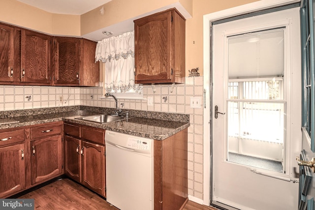 kitchen featuring dishwasher, dark wood-type flooring, backsplash, and a sink