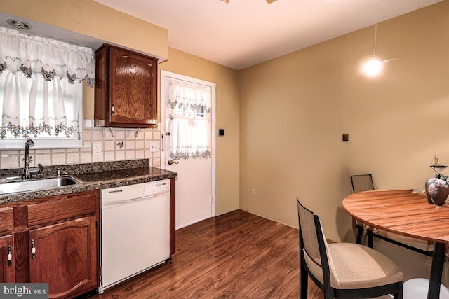 kitchen with dark countertops, tasteful backsplash, dark wood-style flooring, white dishwasher, and a sink