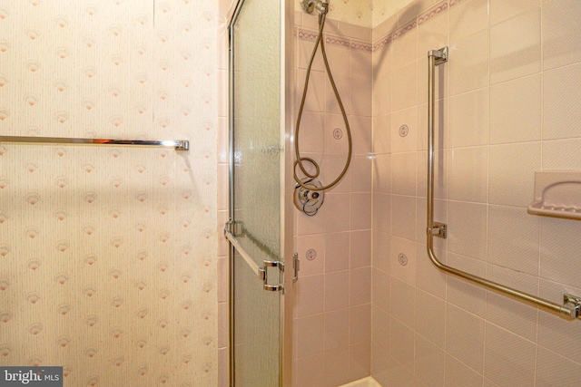 bathroom with a stall shower and wallpapered walls