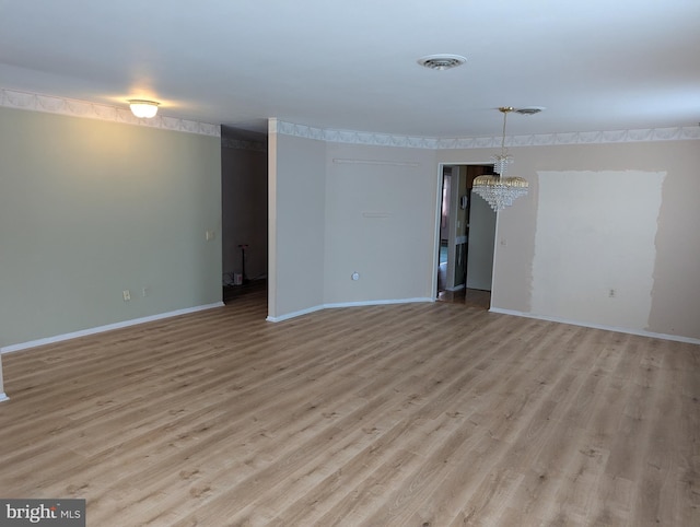 unfurnished living room with light wood-type flooring, baseboards, visible vents, and a chandelier