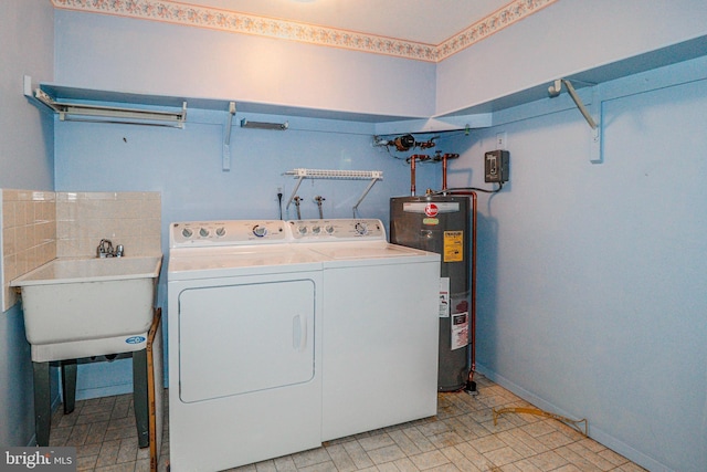 clothes washing area with a sink, baseboards, electric water heater, and independent washer and dryer