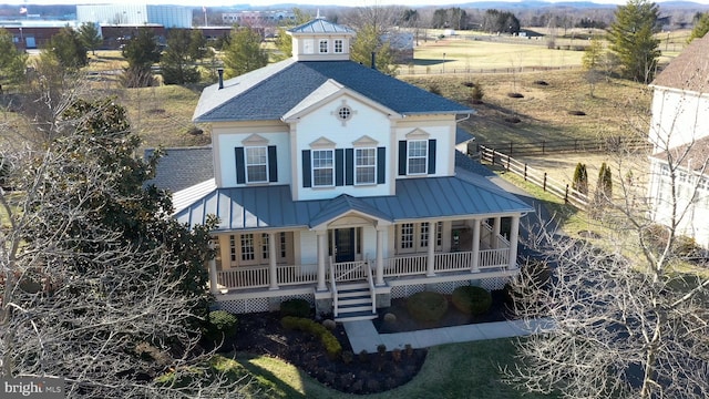 view of front of home featuring fence, a standing seam roof, a porch, a shingled roof, and metal roof