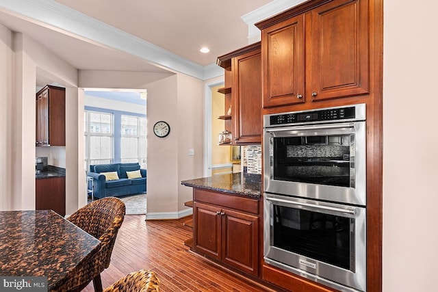 kitchen with backsplash, crown molding, wood finished floors, stainless steel double oven, and open shelves