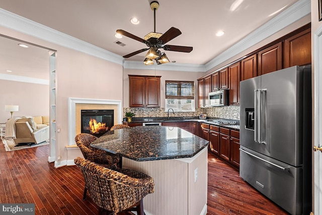 kitchen featuring visible vents, a sink, dark wood-type flooring, appliances with stainless steel finishes, and crown molding