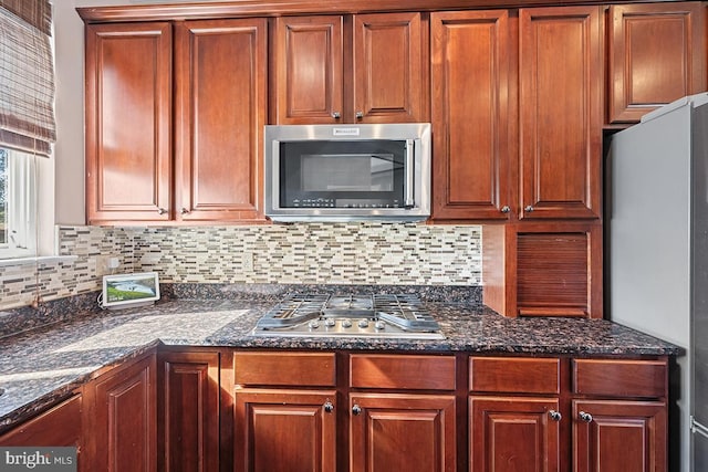 kitchen with tasteful backsplash, dark stone countertops, and stainless steel appliances