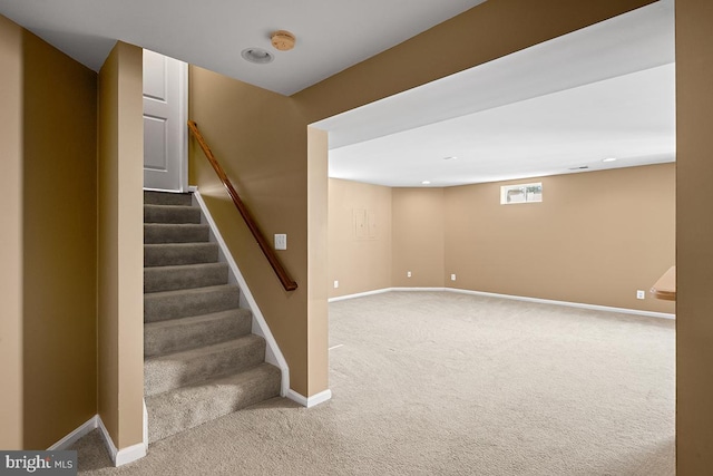 below grade area with baseboards, carpet floors, and stairs