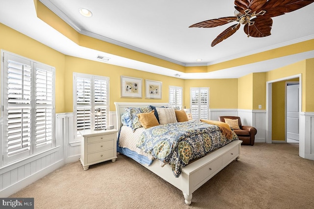 bedroom with visible vents, wainscoting, light colored carpet, and a raised ceiling