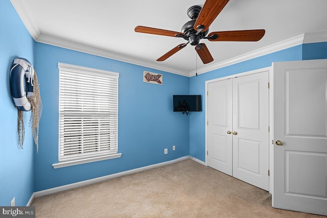 unfurnished bedroom featuring ornamental molding, a closet, carpet flooring, baseboards, and ceiling fan