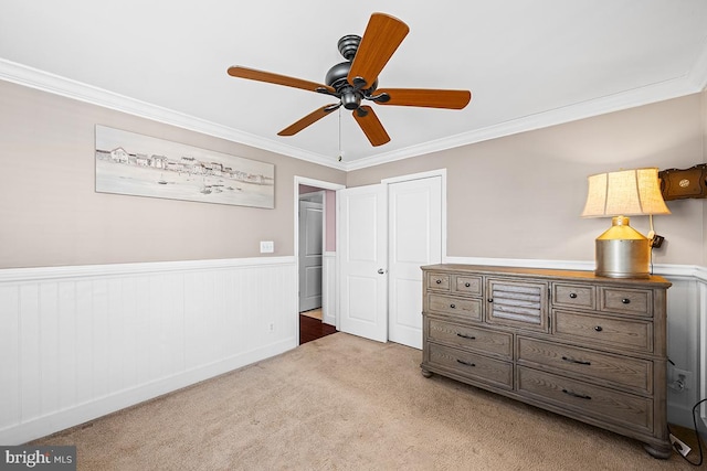 unfurnished bedroom with light carpet, a wainscoted wall, and ornamental molding