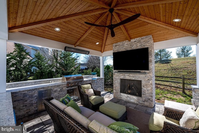 view of patio with grilling area, fence, an outdoor living space with a fireplace, a gazebo, and an outdoor kitchen