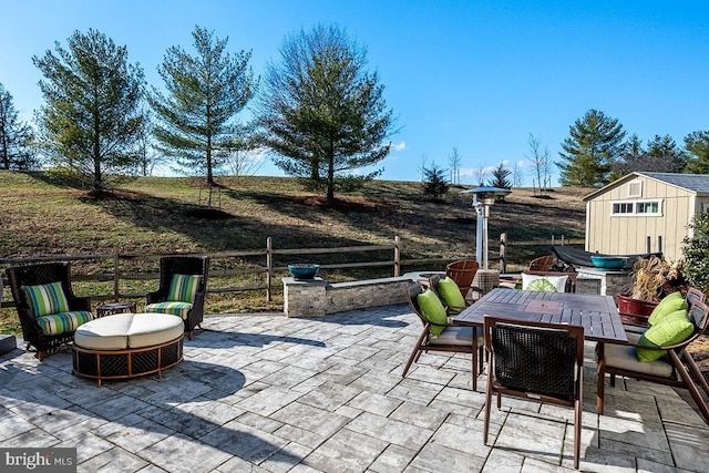 view of patio / terrace with an outdoor structure, outdoor dining space, and a storage shed