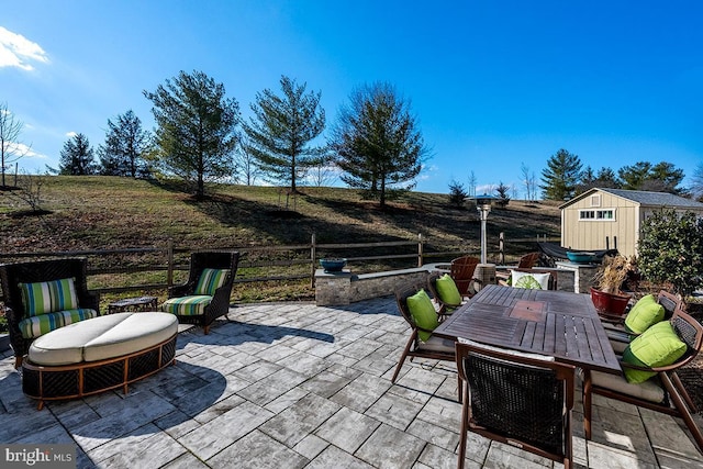 view of patio / terrace featuring outdoor dining area, an outbuilding, and a storage shed