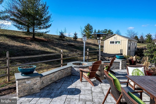 view of patio featuring an outbuilding, a fire pit, fence, and a shed