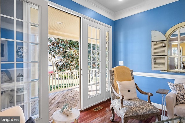 sitting room featuring wood finished floors, visible vents, a wealth of natural light, and ornamental molding