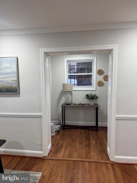 hallway with baseboards, wood finished floors, and crown molding