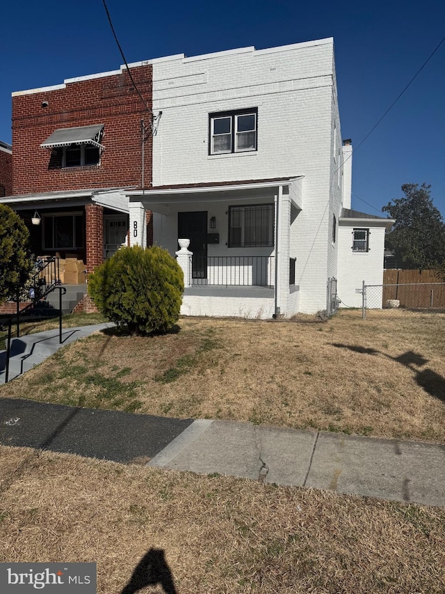 view of front of property with brick siding, a front lawn, and fence