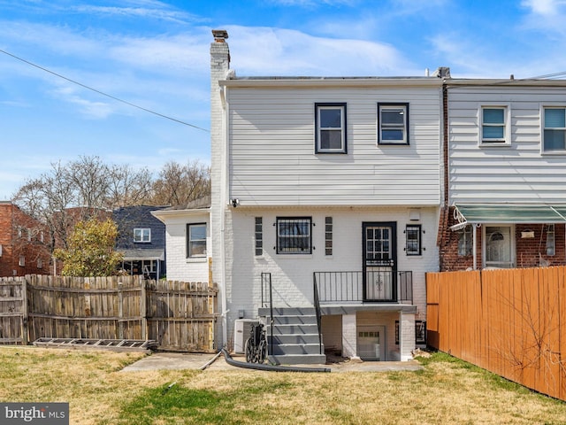 back of property with fence, a yard, a chimney, a garage, and brick siding