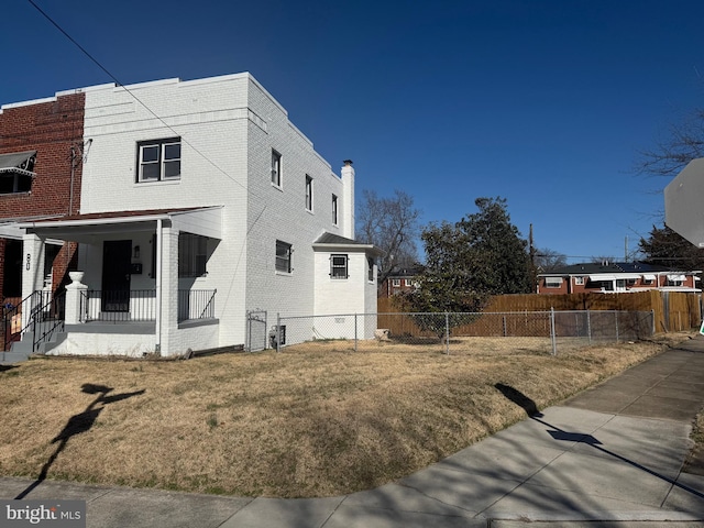 view of home's exterior featuring brick siding, a porch, a yard, and fence