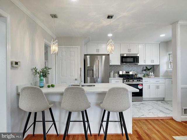 kitchen with a kitchen bar, light countertops, a peninsula, stainless steel appliances, and a sink