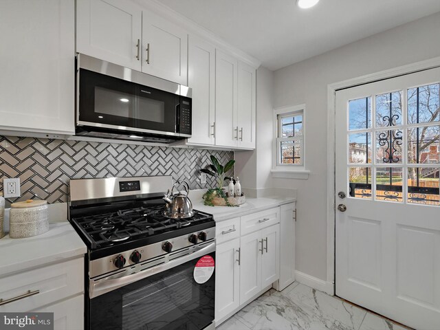 kitchen with baseboards, decorative backsplash, white cabinets, appliances with stainless steel finishes, and marble finish floor