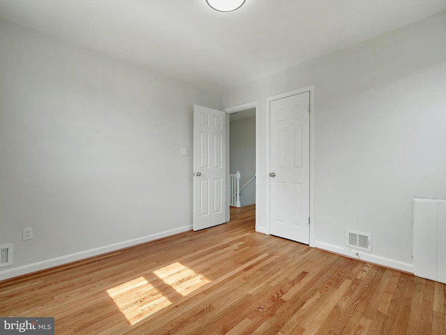 empty room featuring light wood-type flooring, visible vents, and baseboards